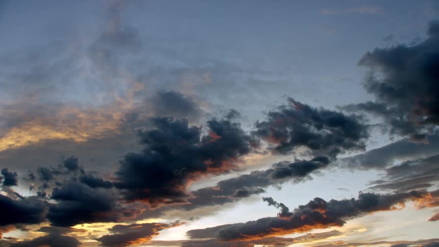 Sunlight shines upon clouds as dark clouds move in front