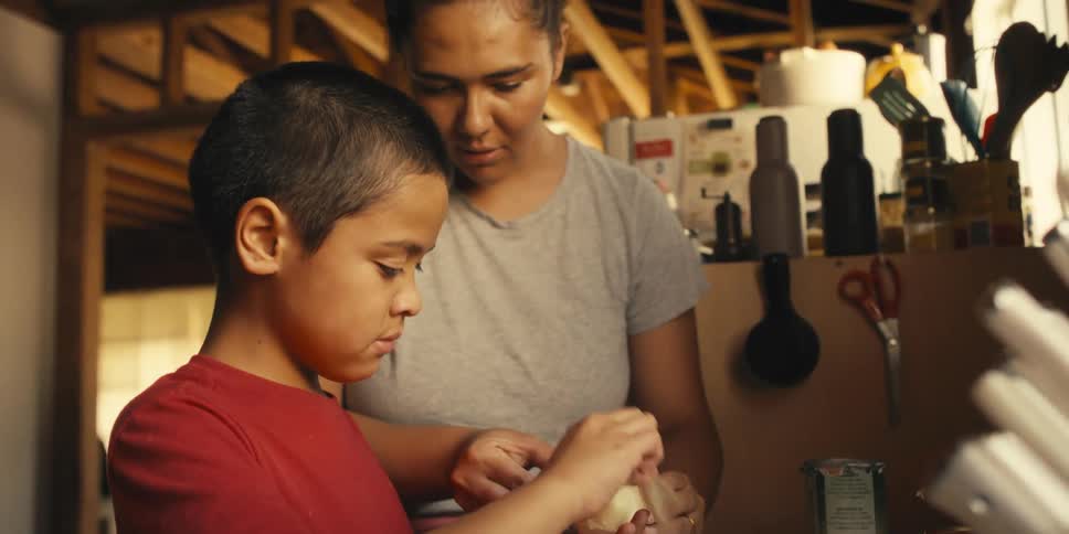 Mother helps her son to peel an onion