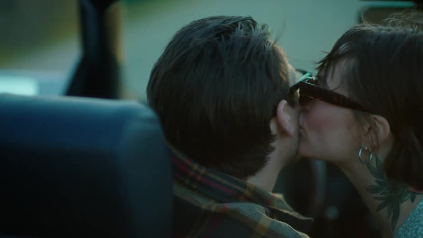 Man driving and a woman kissing him on the cheek