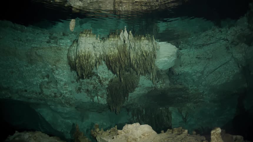 A stone cave under the water and on the surface there are some ripples of waves
