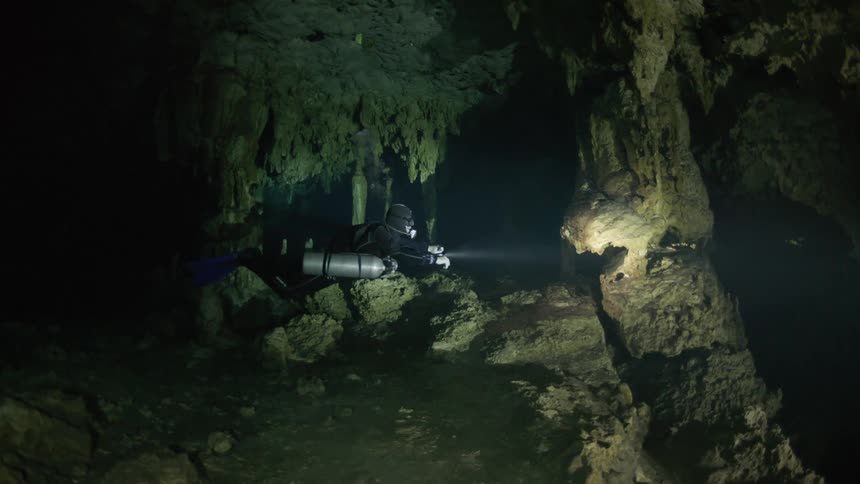 Diver inside a dark cave submerged in water