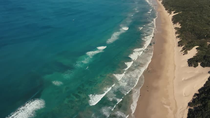 Aerial panorama of a beach with clear waters and a long stretch of sand