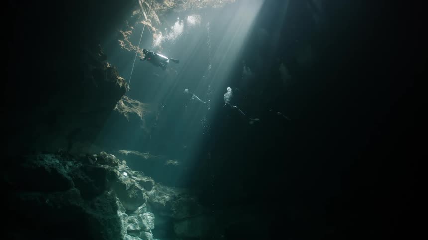 Divers venturing into a cave submerged in water