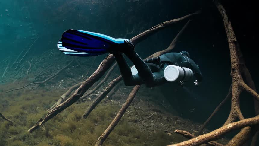 Diver swimming towards an aquatic cave