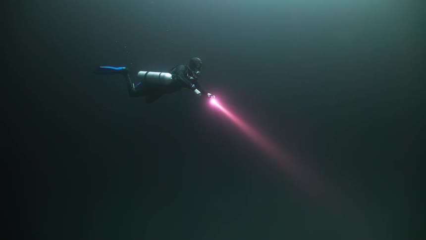 Diver submerged in the ocean with a red light flashlight