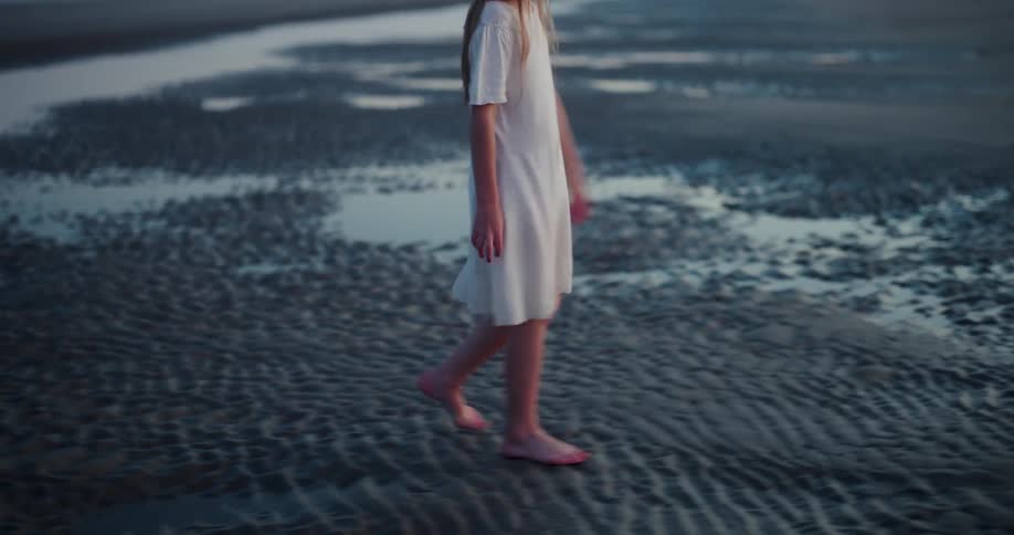 Girl walks barefoot across the wet sand on the beach