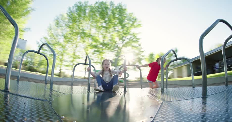 Little girl spinning a toy with another child holding on inside at a park