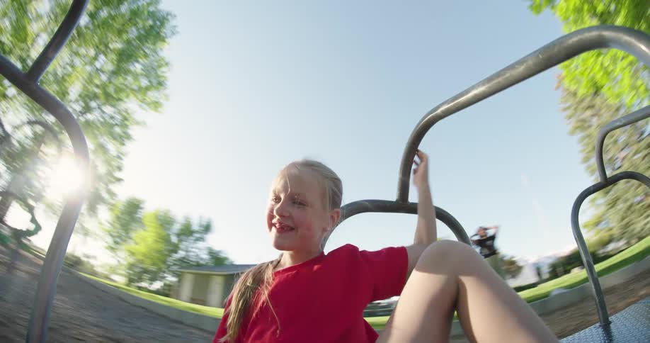Girl having fun on playground equipment with a spinning motion blur