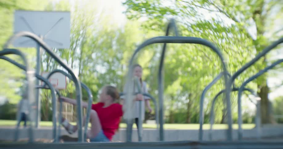 Two young girls play on a merry go round in a park