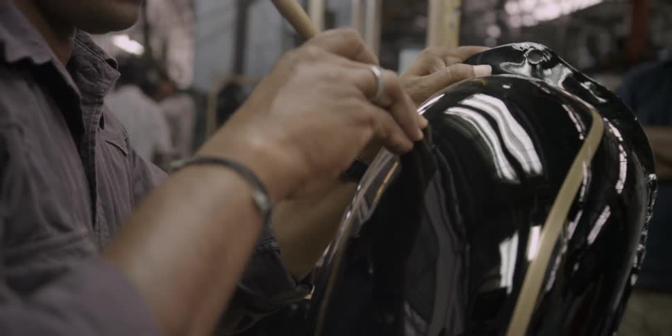 A man is painting a motorcycle piece in a shop