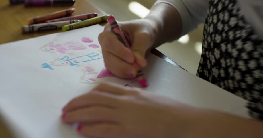 Girl draws on a sheet of paper with crayon