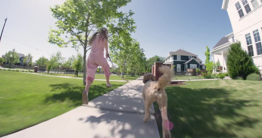Young girl and her dog running on pathway through the neighborhood