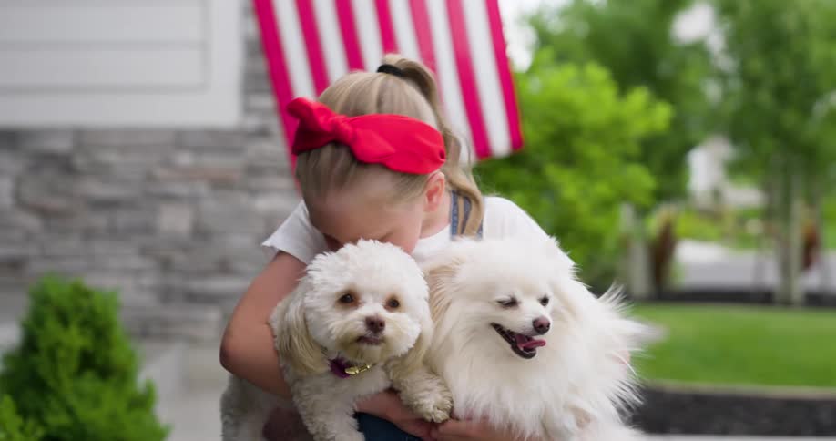 A child is holding and talking to her dogs