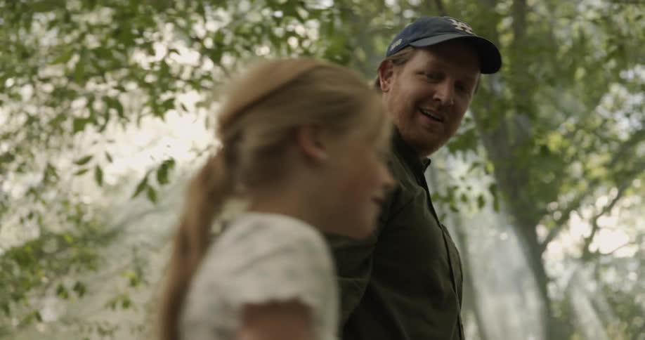 Father and daughter walking together in a forest during the day