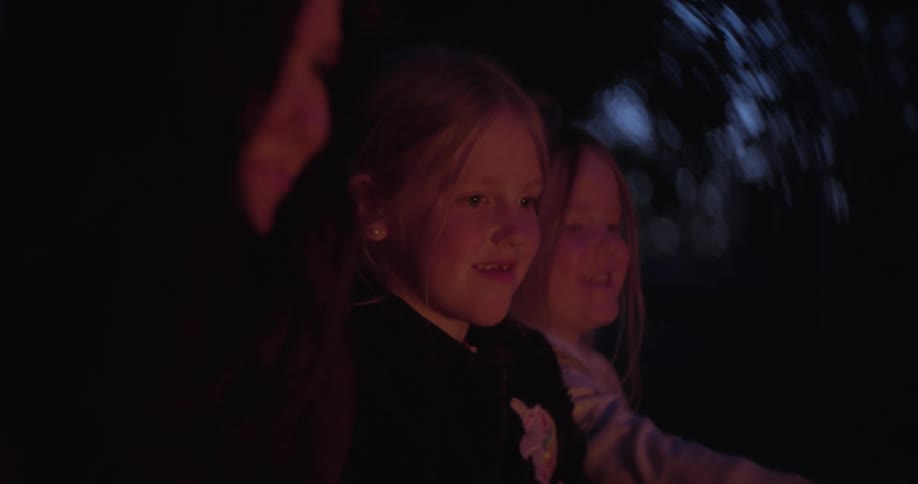 Mother and daughters smiling with glowing faces at dusk