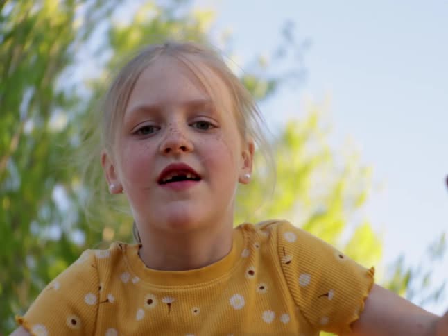 Portrait of a little blonde girl having fun on a swing