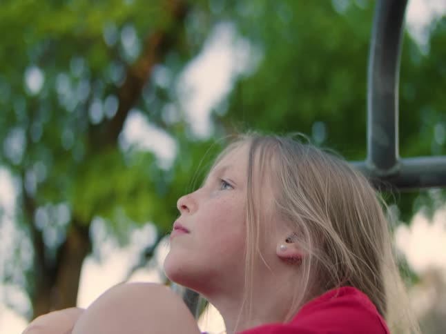 A young girl smiling and looking up while sitting outdoors