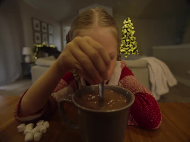 Little girl stirring a cup of hot chocolate
