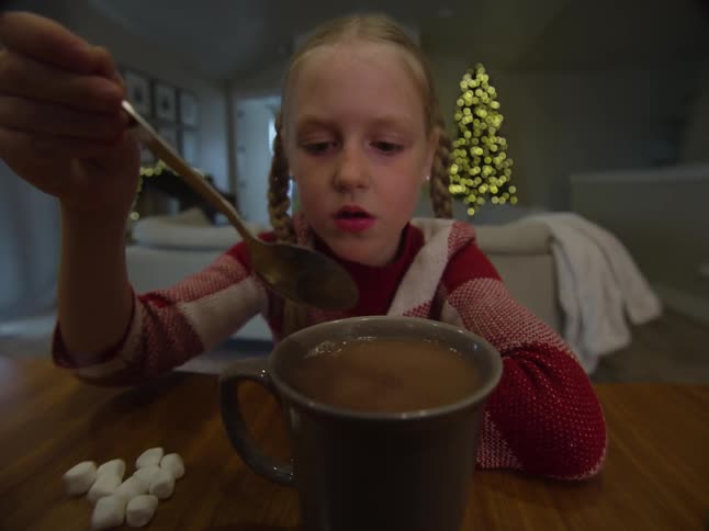 A child is mixing her hot chocolate