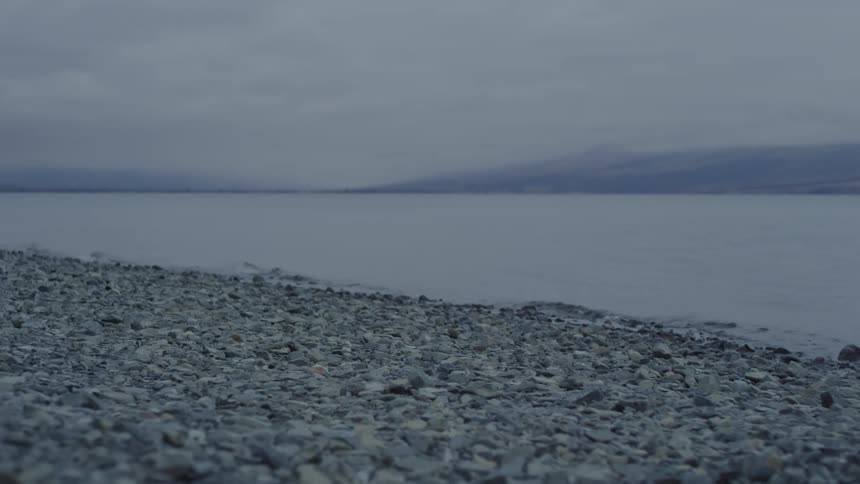 Calm waters of a lake and mountains in the background on a cloudy day