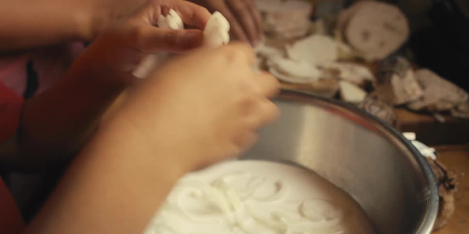 Mother and child add onions to coconut milk while cooking together in the kitchen