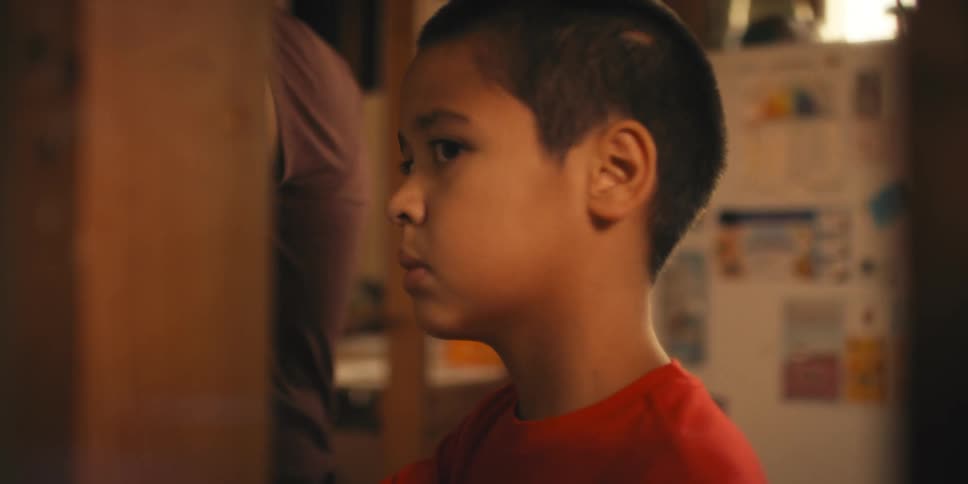 A child standing with his father in a kitchen glances nervously about
