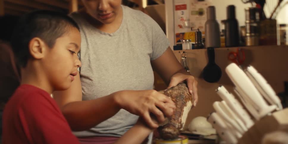 Mother and son in the kitchen peeling a taro