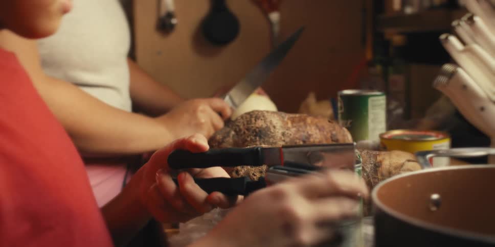 A mother watches as her son opens a can with a can opener