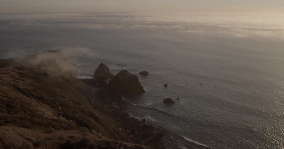 Waves lap the shore of a beach at the bottom of a steep hillside