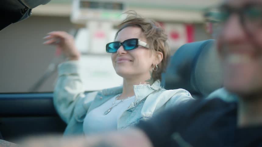 Woman getting into a convertible car next to a man