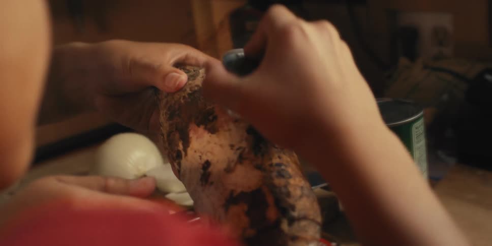 A child is shaving the skin off a vegetable