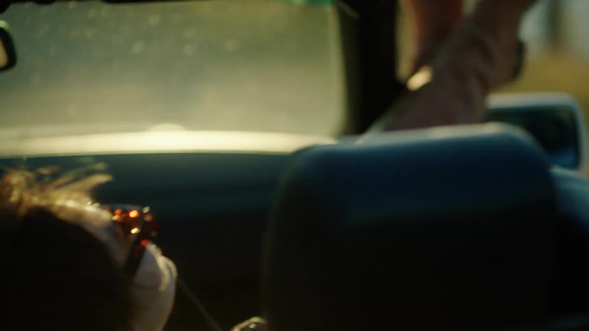 Woman in the passenger seat of a moving car putting her legs out the window