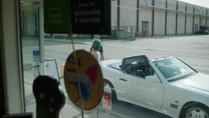 Man and woman getting out of a convertible car and entering a store