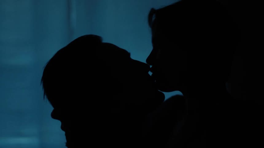 Silhouette of a man and a woman kissing in a dark environment