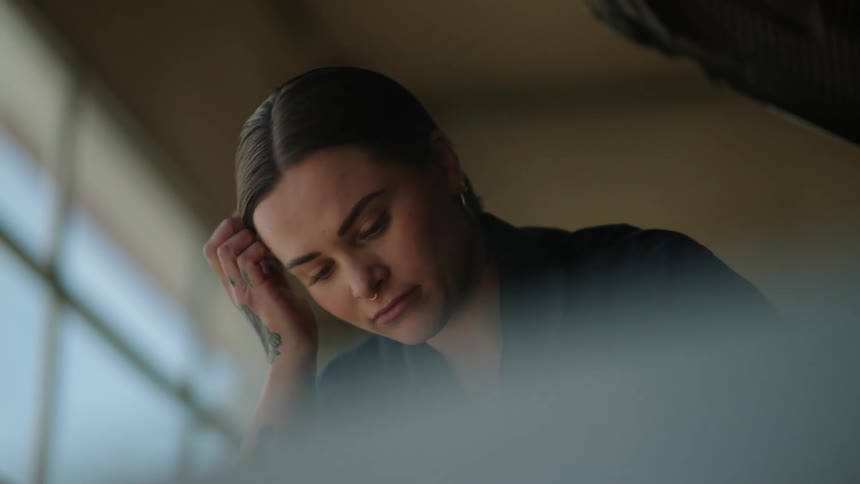 A woman looking down wipes her forehead with her arm