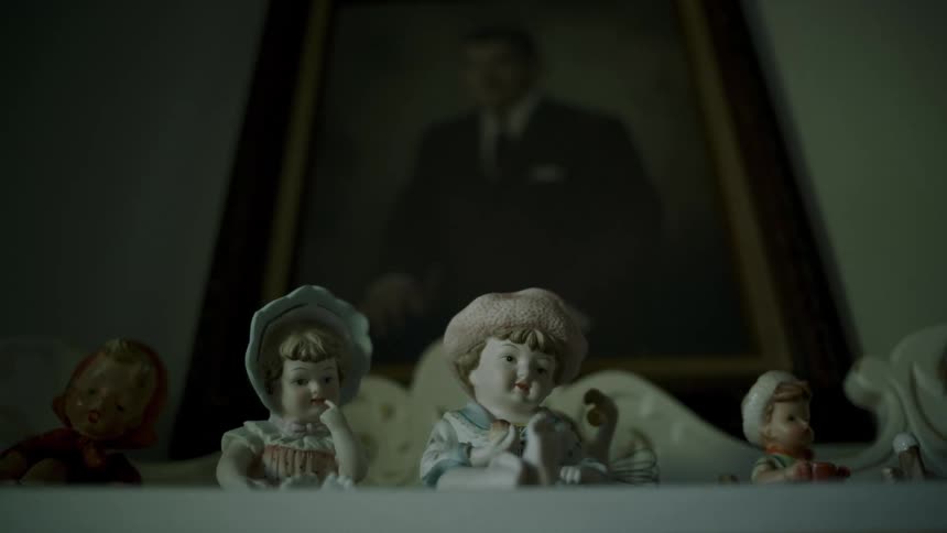 A painting is on the wall and small sculptures are on the mantle