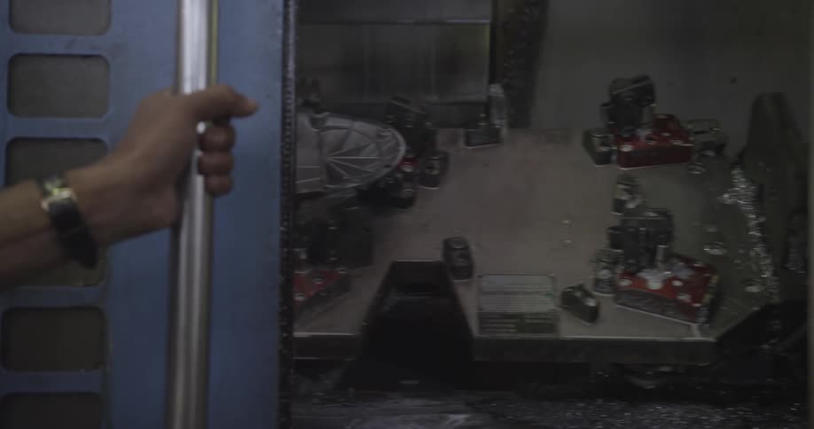 A man is sliding closed a door on some machinery