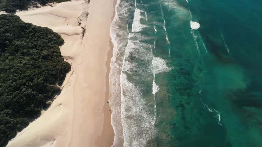 Blue water waves rolling into shore and over the beach
