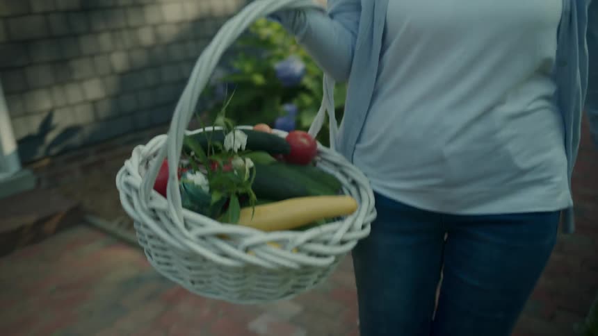 Woman carrying a white basket with colorful vegetables