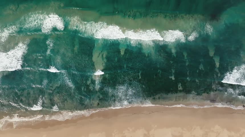 Aerial view of a turquoise blue sea with a vast expanse of sand