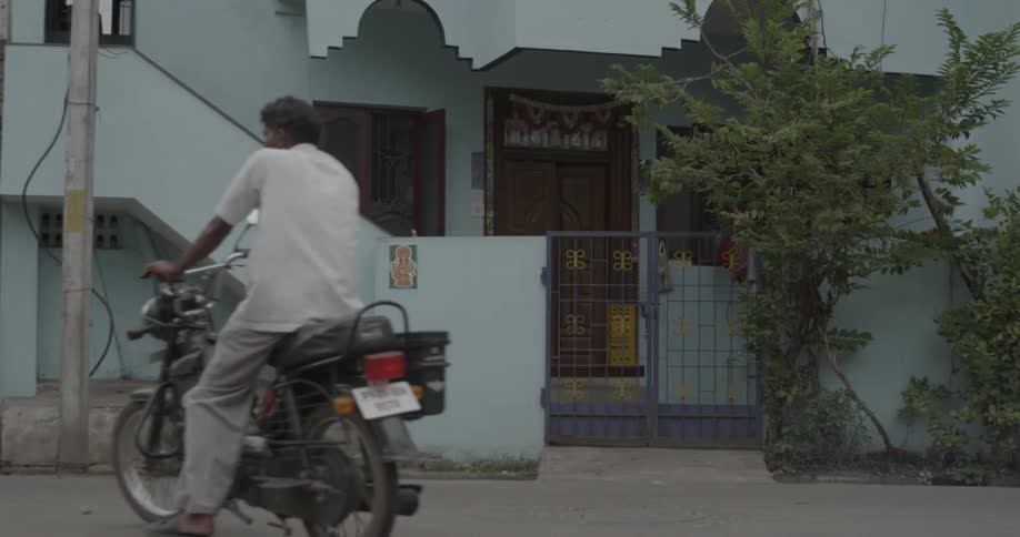 A man rides his motorbike towards the building