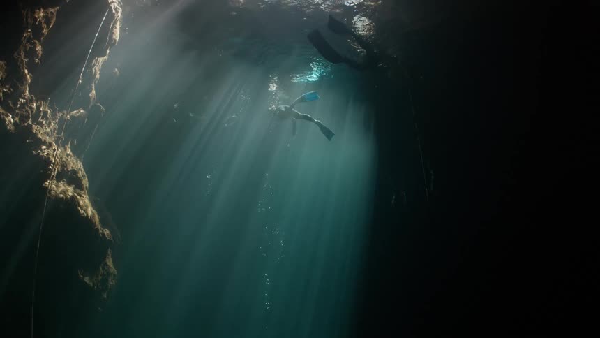 View from inside a lake with a diver and the reflection of sunlight