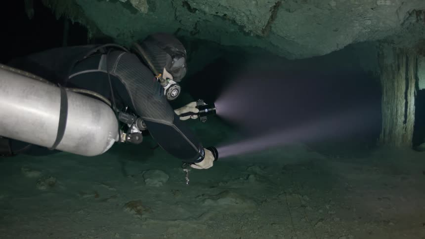 Diver submerged in a dark cave underwater