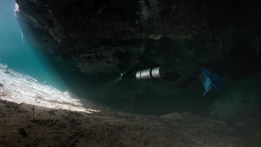 A person is scuba diving in the dark cave