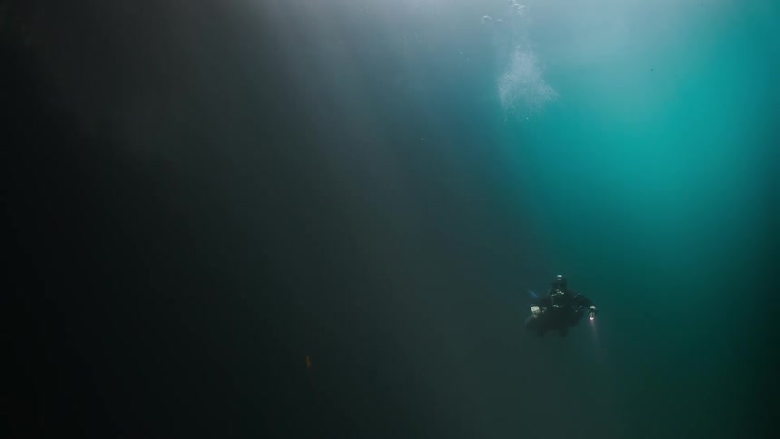 A scuba diver is swimming deep underwater