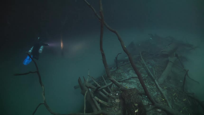 Diver with a flashlight venturing to the bottom of the ocean