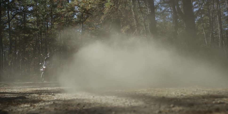 People riding dirt bikes on dirt road in woods