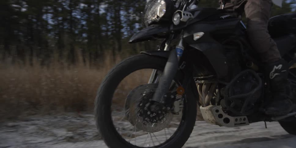 A person stands up while riding a motorcycle on a dirt trail