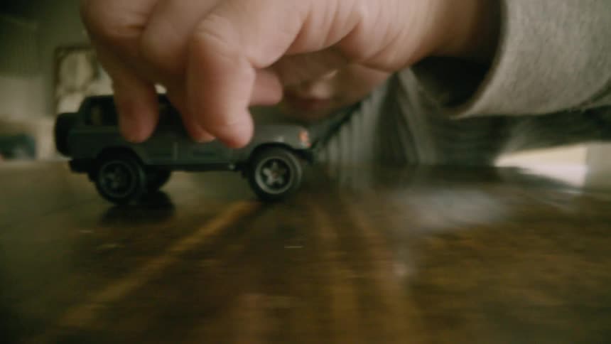 Close up of a boy playing with a toy pickup truck over a table