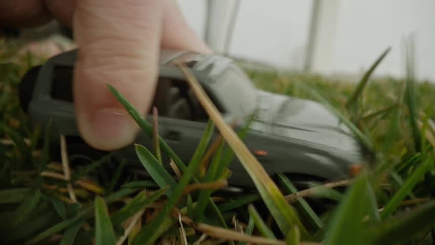 A person plays with a toy car in a yard